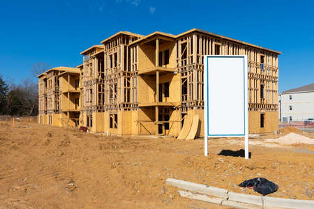 Horizontal shot of a blank white sign in front of a new apartment complex under construction.