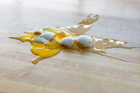 Horizontal shot of a dropped and broken white chicken egg on the floor with copy space.の写真素材