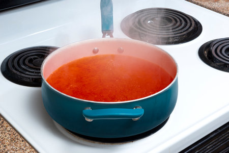 Horizontal angled shot of a blue pot on a stove top holding hearty tomato soup that is simmering.