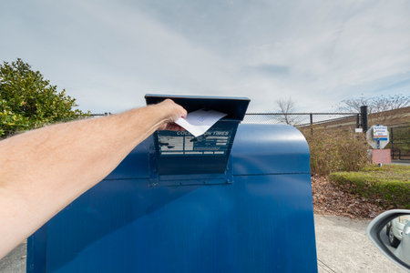Horizontal shot of a manâs arm putting a letter in a mailbox slot.の写真素材