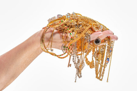 Horizontal shot of a womanâs hand holding gold jewelry isolated on white.の写真素材