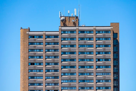 Horizontal shot of a high-rise apartment building with communications equipment on the roof under a...