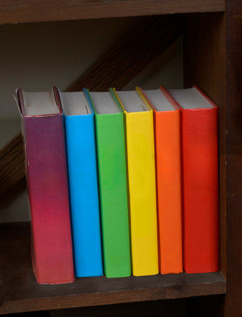 Vertical shot of a row of multicolored hardbound book with blank spines.の写真素材
