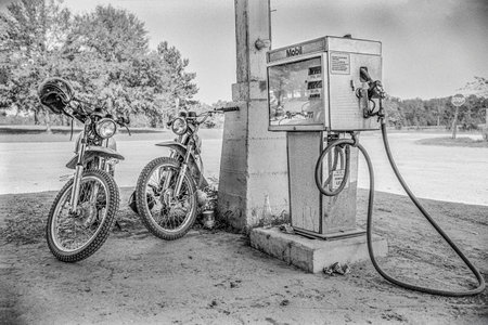 Macedonia, Arkansas, United States â June 23, 2024: Horizontal shot of two vintage era dirt bikes next to an old Mobil gas pump in 1975.のeditorial素材