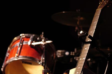 Partial drum kit and guitar in subdued stage lighting.の写真素材