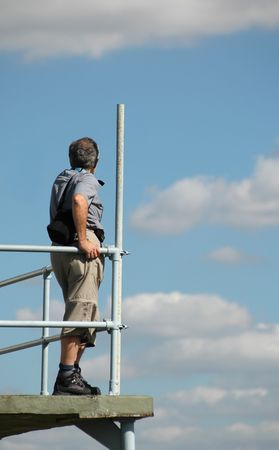man viewing clouds from airfield observation platform