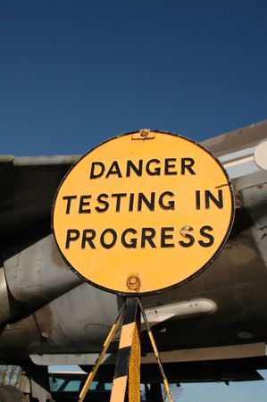 danger sign in front of vintage military jet