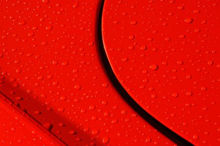 background of raindrops on a red sports car panelの写真素材