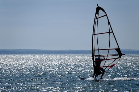 windsurfer silhouette against a sparking blue seaの写真素材