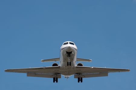 business jet on landing approach against a clear blue sky