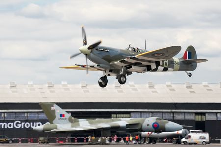 FARNBOROUGH AIRSHOW, UK - JULY 24, 2010: WW2 Spitfire coming into land with XH558 Vulcan bomber in the background.のeditorial素材