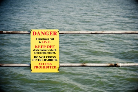 danger sign for electrified third rail near waterの写真素材