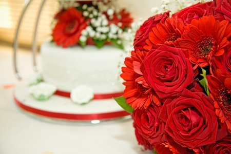 red wedding flowers with wedding cake in the backgroundの写真素材