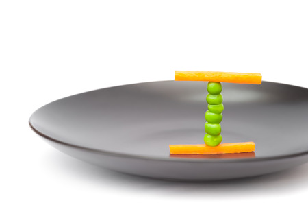 balanced diet food concept using peas and carrots on a plateの写真素材