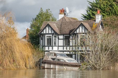 Windsor, UK - 11 February, 2014 - Rising water levels push a motorboat against a family home during flooding on the Thames River near Windsor, UKのeditorial素材