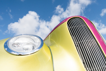 restored classic car radiator grille closeup against blue skyの写真素材