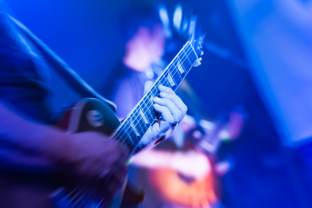 musician playing an electric guitar under blue stage lightingの写真素材