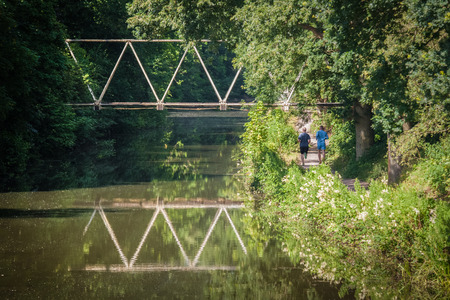fit male joggers on a canal path run during summerの写真素材