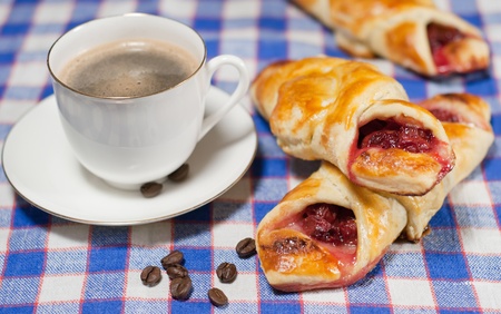 cherry bun on a plate and cup of coffeeの写真素材
