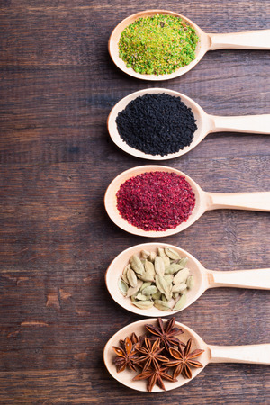 Assorted powder spices in wooden spoons on wood の写真素材
