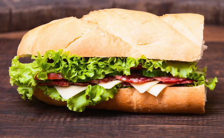 Sandwiches - turkey breast, ham and swiss and salami on old cutting board.の写真素材