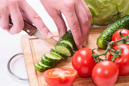 Closeup Of Young Woman In Kitchen Cutting Vegetablesの写真素材