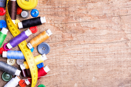 Spools of threads and buttons on old wooden table