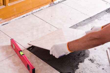 Tiler installing ceramic tiles on a floorの写真素材