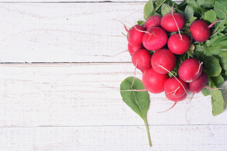 bundle of bright fresh organic radishes with leaves on wooden backgroundの写真素材