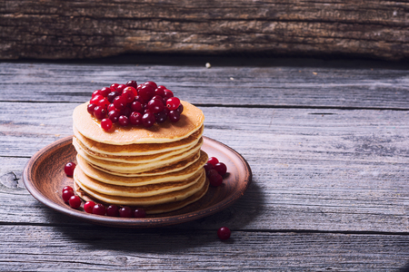 A stack of pancakes with cranberries on wooden backgroundの写真素材