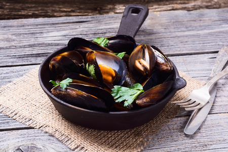 Mussels with parsley in pan on rustic wooden backgroundの写真素材