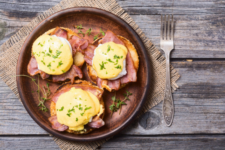 Eggs benedict with bacon on wooden background . Top view . Space for textの写真素材