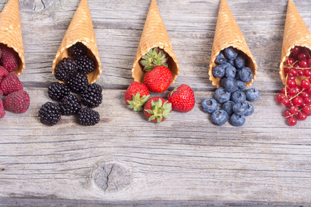 Berries in ice cream cone (raspberry , blueberry , strawberry , red currant , blackberry)  with space for textの写真素材