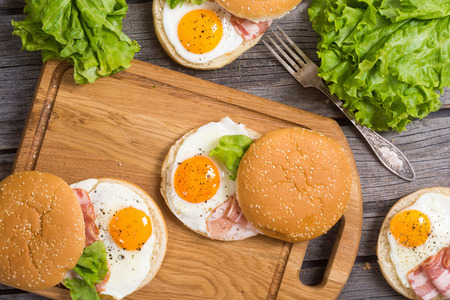 Sandwich with eggs , salad and bacon on wooden table , top viewの写真素材