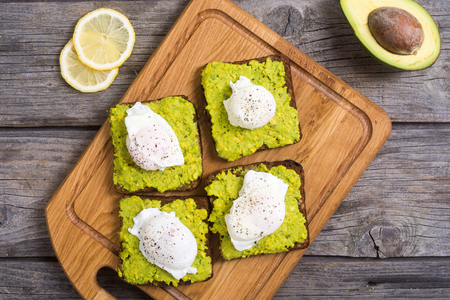 Poached egg and avocado mexican sauce guacamole on toast . Top viewの写真素材