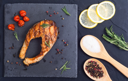 Grilled salmon steak with tomato , lemon and rosemary . Top viewの写真素材