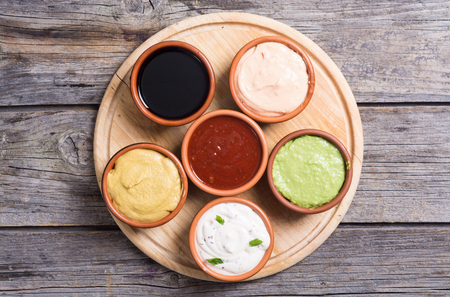 Set of sauces in bowl on wooden background