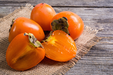 Delicious ripe persimmon fruit on wooden backgroundの写真素材