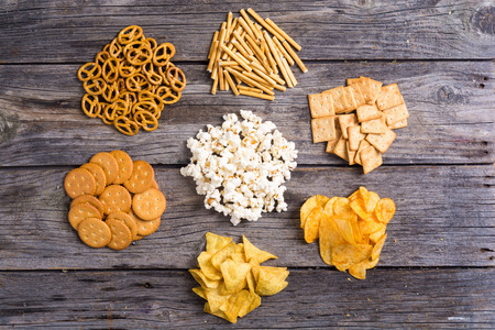 Frame . Mix of snacks : pretzels , crackers , chips , pop corn and nachosの写真素材