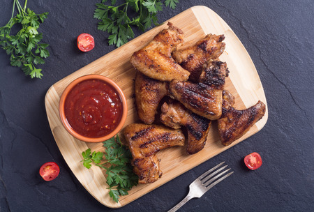 Grilled chicken wings with sauce , tomato and parsleyの写真素材