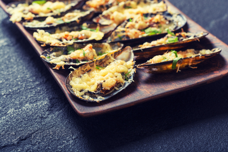 Mussels baked with cheese and parsley . Seafood backgroundの写真素材
