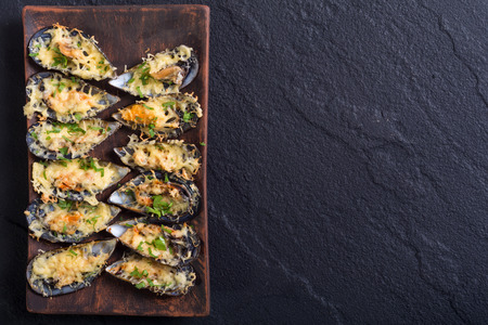 Mussels baked with cheese and parsley . Seafood backgroundの写真素材
