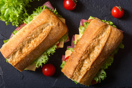 Ciabatta sandwich with lettuce , salami , cheese , avocado and tomatoesの写真素材