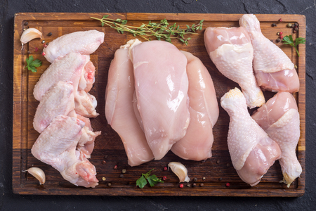 Raw chicken meat on cutting board . Legs , wings and breastの写真素材