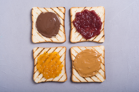 nut nougat cream with chocolate , strawberry, apricot jam and peanut butter sandwichの写真素材