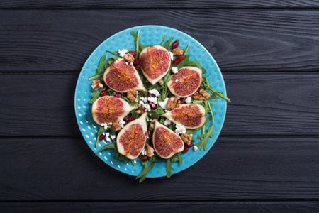 Figs autumn salad with cheese , arugula , walnuts and pomegranate . Healthy food