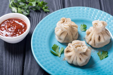 Georgian dumplings khinkali with tomato sauce and parsleyの写真素材