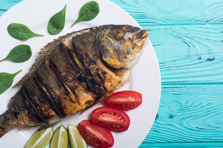 Fried fish dorado with lime , tomatoes and spinach . Sea food backgroundの写真素材
