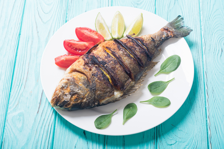 Fried fish dorado with lime , tomatoes and spinach . Sea food backgroundの写真素材
