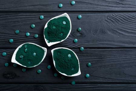 Ground spirulina and spirulina in pills . Healthy vegan superfood backgroundの写真素材